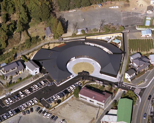 上空から見た、円形の中庭を囲むドーナツ形の温泉会館と駐車場