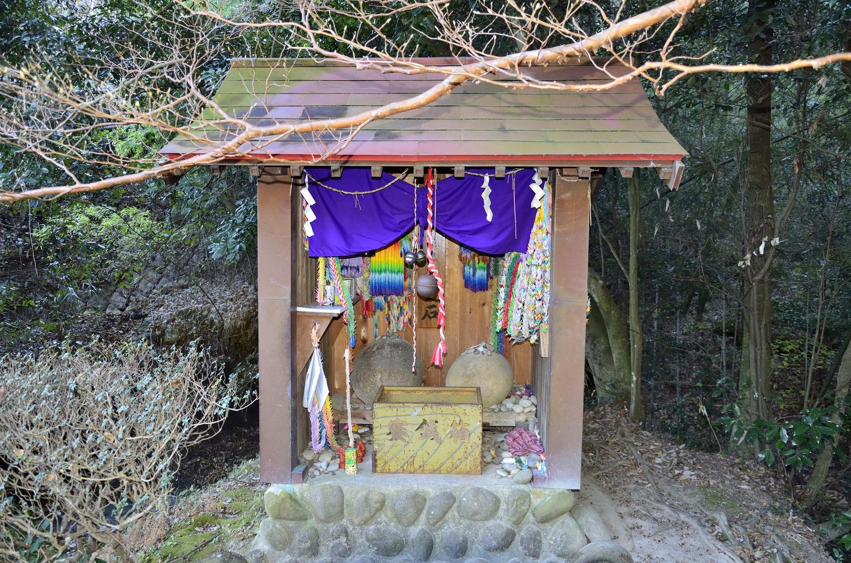 千羽鶴が奉納された小さなお堂にまつられた二つの丸い子生れ石