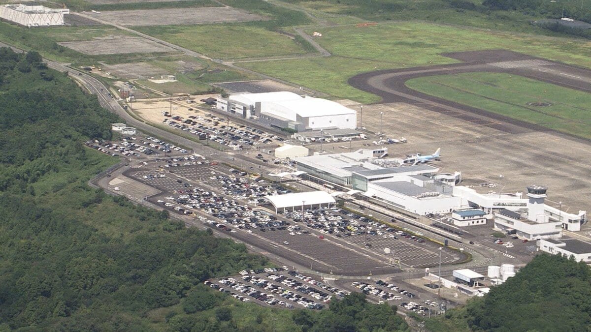 緑の丘の上に広がる空港ターミナル、駐車場、滑走路を上空から見た様子