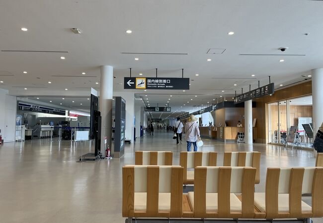 国内線到着口の案内表示とベンチが並ぶターミナル内部