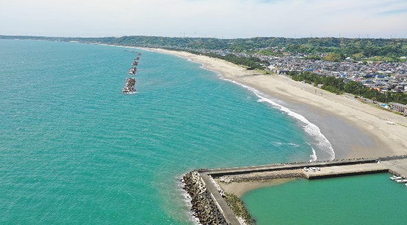 上空から見た、エメラルド色の海と弓なりに続く相良海岸の砂浜
