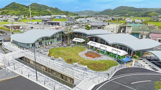 上空から見た、銀色の曲面屋根が連なる道の駅と中央の芝生広場